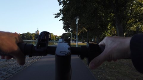 POV rides an environmentally friendly e-scooter on a city shore
