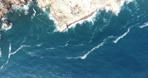 Aerial view of Cape San Antonio, Denia, Valencia. Rocky cliff revealing sea waves crushing on the coastline. Blue water in a sunny day.