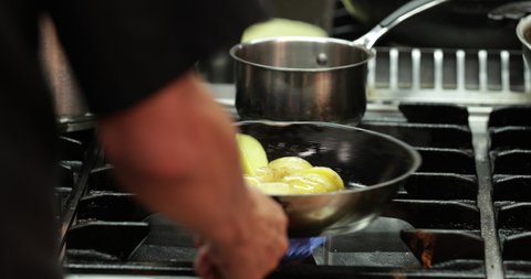 Chef Holding And Spinning Chopped Potatoes In A Frying Pan With Hot Oil In The Kitchen Of A Restaurant. - close up shot