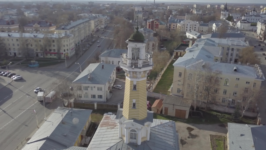 Aerial view of Fire Tower Kostroma city, Russia. Cityscape, orthodox temple, houses on background. Russian old historical town. Spring, sunny day, street with going cars, bare trees