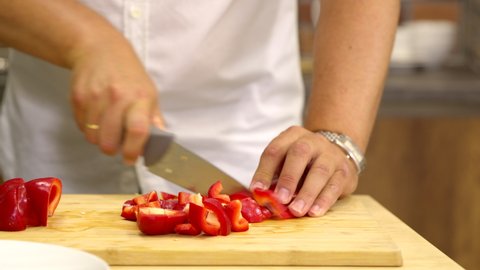 Close up view of male cook cuts fresh red pepper into slices. Man cooking vegan side dish healthy dietary food, home-cooking tips, online culinary courses cooking classes, kitchen lifestyle concept