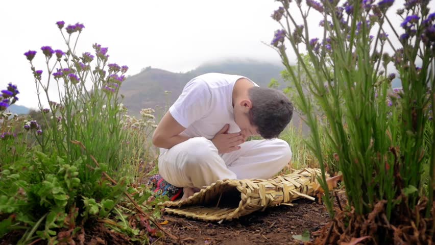 Young man meditating on top of high mountain on spring blooming