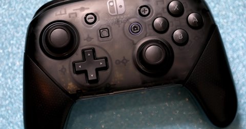Paris, France - October 16 2020: Overhead View And Rotation Of A Nintendo Switch Pro Wireless Controller On Shiny Blue Background. Close Up Macro View - DCi 4K Resolution