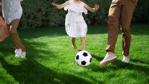 Parents and children feet playing football outdoors. Closeup father throwing soccer ball in air. Small kids trying to get ball. Active family spending time together in park