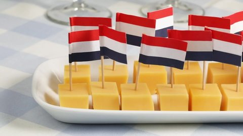 Dish with cubes of mature Dutch Gouda cheese and flag sticks as a traditional snack close up