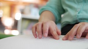 Close-up of disability blind person woman hands moving fingers reading Braille book studying in creative library. Braille is a system of raised dots that can be read with the fingers - Powered by Shutterstock - Get 15% off with code: PIKWIZARD15