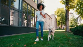 African american girl walking with white labrador along lawn