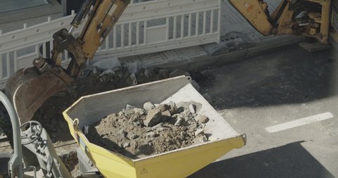 Digging Machine loading debris in a dumper. Repair work on the city street. Slow motion