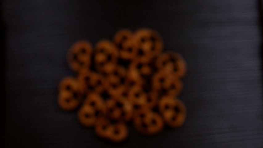 Salty pretzels fly up and hang in the air on a black background