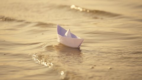Paper boat in the river. Paper children's toy. The paper boat sways on the waves