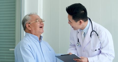 Happy Asian elderly man patient Have fun talking with professional man doctor at hospital. Old man patient talk with doctor about result of health check up report.