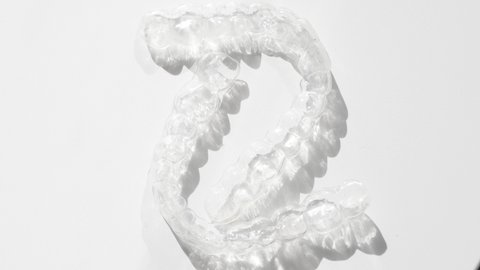 teeth removable and invisible retainer on white surface, modern  transparent aligners or braces to straighten teeth in cosmetic dentistry and orthodontics