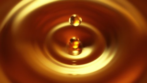 Super Slow Motion Shot of Droplet Falling into Golden Liquid at 1000fps.