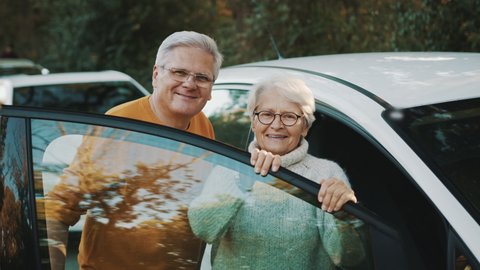 Senior couple purchased new car. Standing near the door and smiling. High quality 4k footage