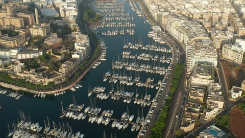 Sailboats and regular Boats sitting in Marina Port on Malta Island, Aerial tilt down View