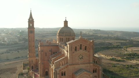 Beautiful Sand Brown Colored Church in Countryside of Gozo, Malta in beautiful afternoon sunlight, Aerial slide right