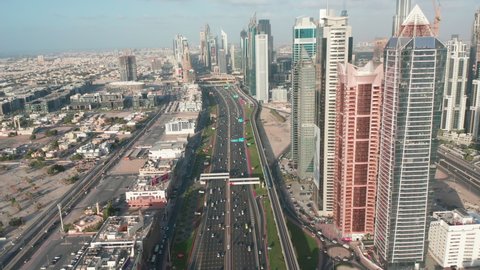 Dubai rush hour traffic and metro trails passing from above overhead view, aerial footage of Sheikh Zayed Road panning down from skyline