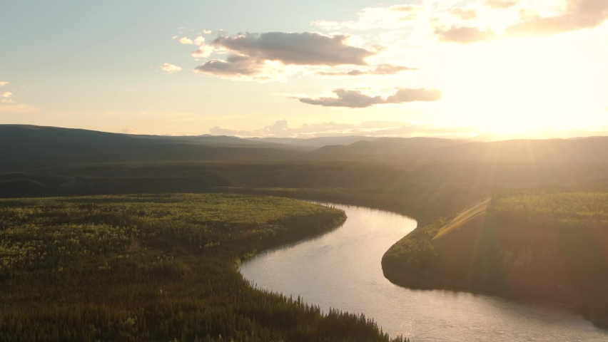 Beautiful View of Scenic Winding River, surrounded by Forest and Mountains at Sunset. Aerial Drone Shot. Taken near Klondike Highway, Yukon, Canada. 4K Royalty-Free Stock Footage #1060747204