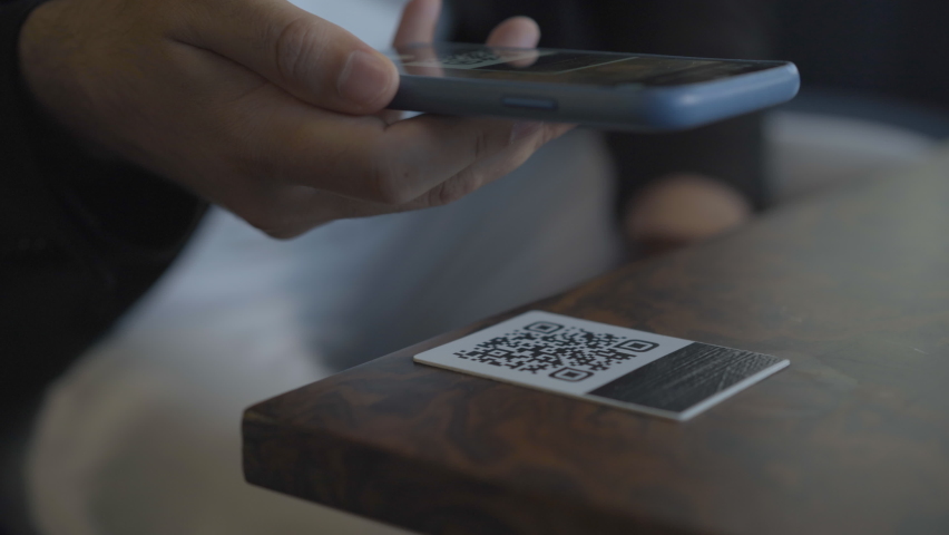 Unrecognizable Caucasian man scanning QR-code with smartphone. Male hands holding phone and tapping on screen. Modern menu in cafe or restaurant. | Shutterstock HD Video #1060748968