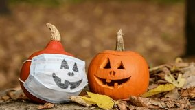 Two Halloween orange pumpkins, one in medical mask with drawn face, lies on fallen leaves in autumn forest. Few leaves falls down. Selective focus. Theme of Halloween during coronavirus pandemic. - Powered by Shutterstock - Get 15% off with code: PIKWIZARD15