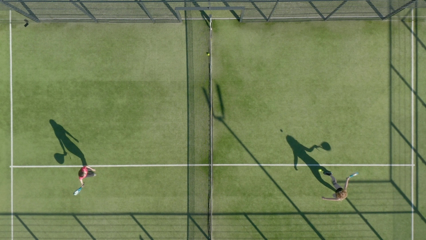 Aerial, top down, drone shot, rising above people playing tennis. 
Two girls play padl tennis Royalty-Free Stock Footage #1060751680