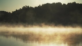 Fog on lake. Golden sunlight rising moving orange mist on water surface in autumn. Forest background and beautiful peaceful reflections  - Powered by Shutterstock - Get 15% off with code: PIKWIZARD15