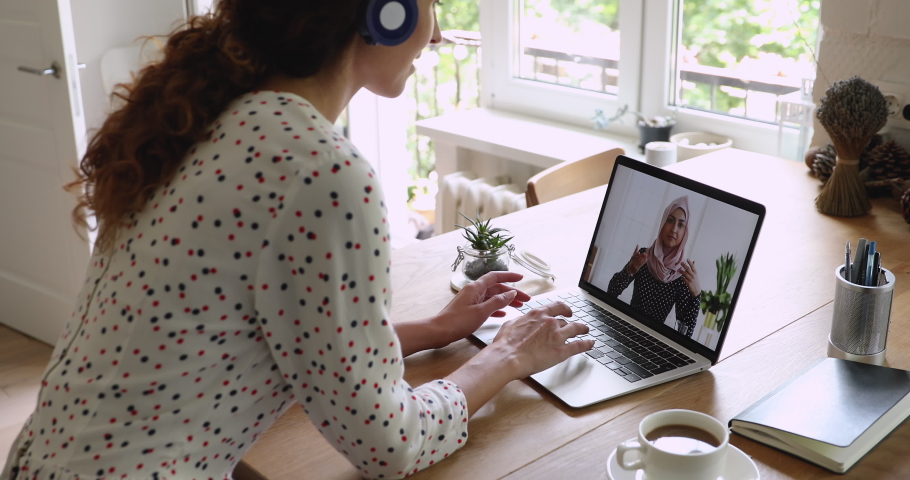 Multiracial businesswomen negotiate using laptop and video call app, screen view where female in hijab talks with colleague, businesspeople work distantly solve issue share thoughts at virtual meeting Royalty-Free Stock Footage #1060757536