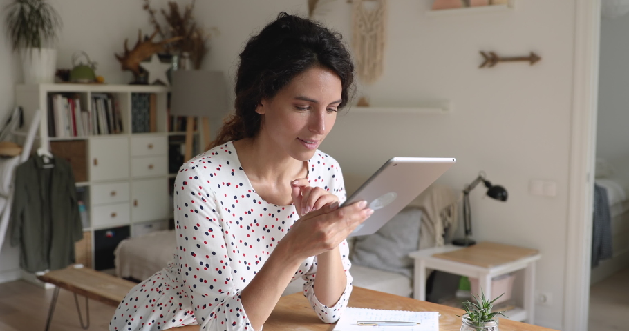 Woman standing in living room hold tablet device do telework from home. Female shopper enjoy e-shopping purchasing fashion clothes on-line. Freelancer distracted from work have fun on internet concept Royalty-Free Stock Footage #1060757584
