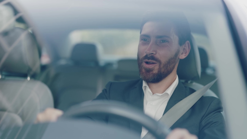 Smiling young attractive man beard driving car. Feel happy. Young businessman at sunlight. Close up. Automobile work city. Slow motion | Shutterstock HD Video #1060757635
