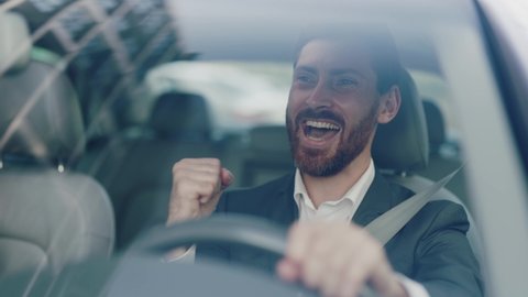 Smiling young attractive man beard driving car. Feel happy. Young businessman at sunlight. Close up. Automobile work city. Slow motion