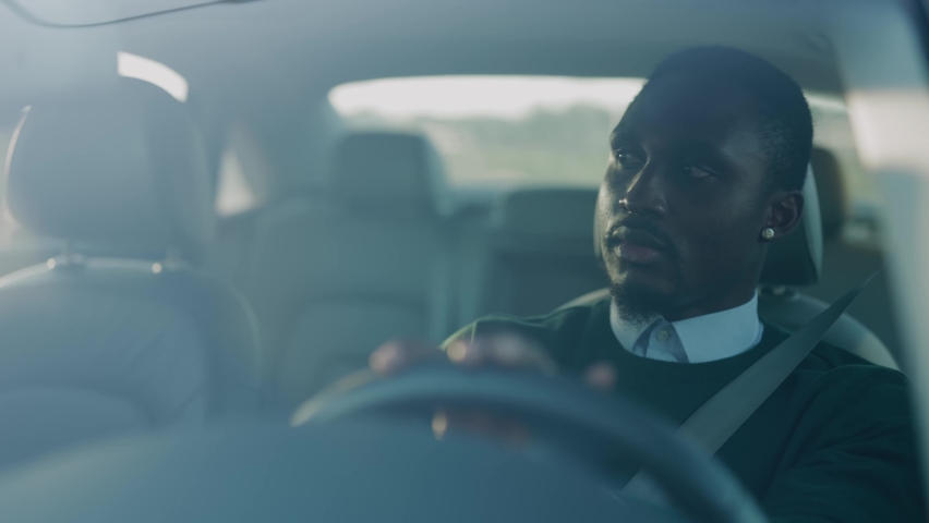 Attractive young african american man driving car with passenger. Serious man at sunlight. Automobile businessman traffic transportation. Slow motion Royalty-Free Stock Footage #1060757674