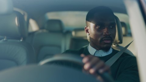 Attractive young african american man driving car with passenger. Serious man at sunlight. Automobile businessman traffic transportation. Slow motion