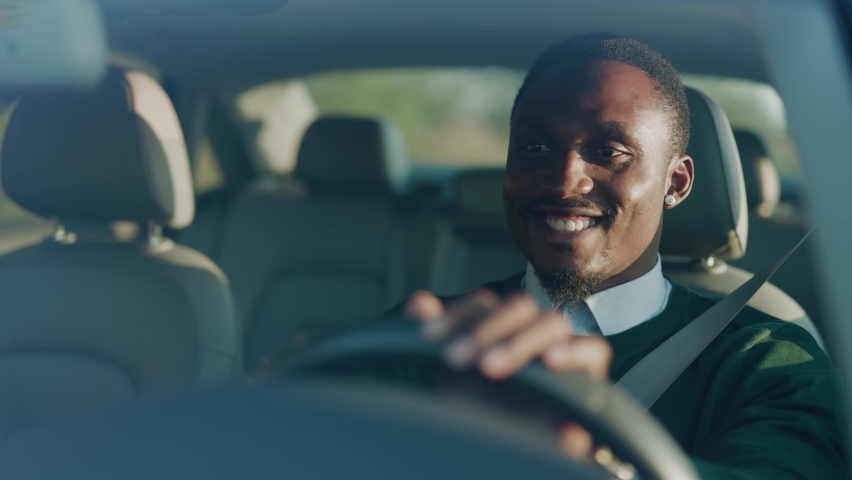 Funny young african american man smiling driving car with passenger. Feel happy at sunlight. Automobile businessman traffic transportation. Slow motion Royalty-Free Stock Footage #1060757677