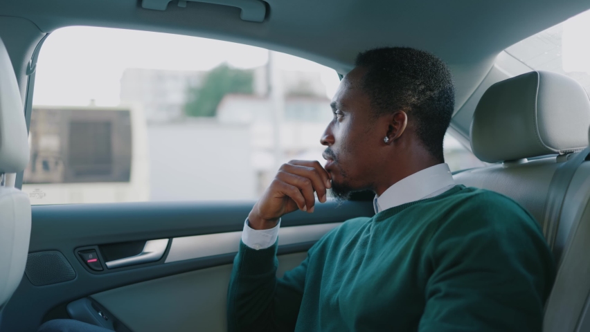 Focused stylish young african american man sitting in car at backseat. Serious businessman. Communication passenger worker. Slow motion | Shutterstock HD Video #1060757689