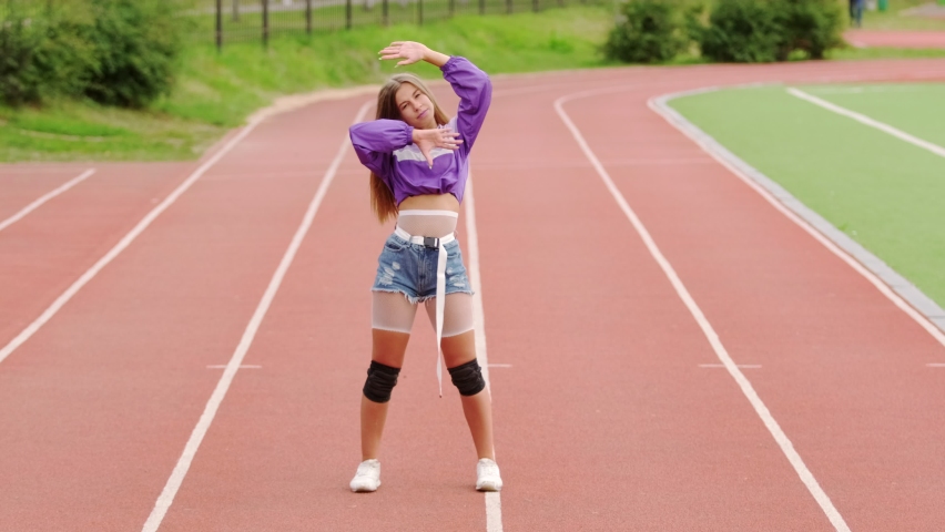 Young beautiful woman dancing dancehall with twerking elements on stadium running track