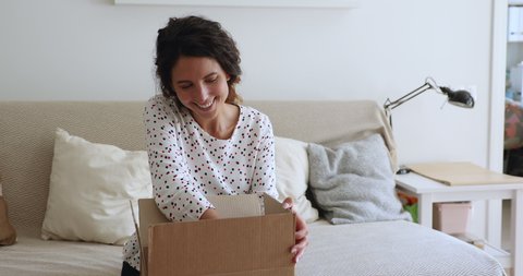 Woman sit on couch use phone check delivery date, package arrived on time, texting to sender gift was received feels satisfied, girl opens parcel box enjoy moment, online app and retail webshop client