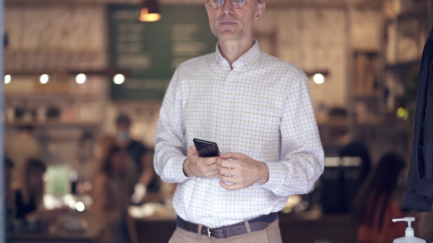 Serious adult man standing in the cafe and looking at the camera. Slowmotion.