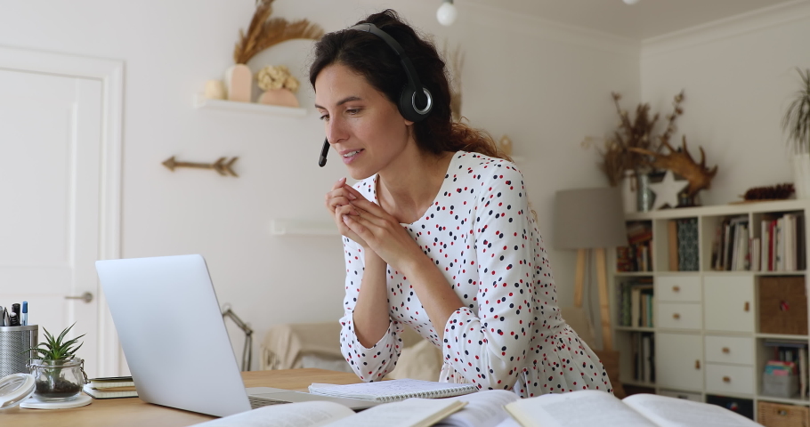 Woman in headset talking lively while participates in webinar professional development gain new knowledge share ideas with mate using laptop internet and video call app, e-coaching and e-learn concept Royalty-Free Stock Footage #1060767109