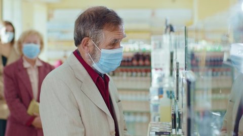 Slow motion people standing in line in the pharmacy. In medical masks. Inside. Quarantine safety pandemic sick doctor buy infection drugstore respiratory.
