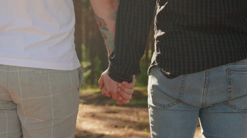Close Up of Two Male Hands Gently Touching and Holding Each Other. Cute Queer Relationship Concept. Gay Couple Dating During Summertime. LGBTQI, Pride Event, LGBT Pride Month, Gay Pride Symbol