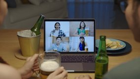 Zoom out : Young happy asian couple enjoy relax night party event online celebration festive with friends at home clinking beer with glass and bottle toasting drinking via video call.