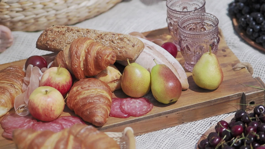 Outdoor picnic - fruits and pastries on wooden tray and table cloth. Fresh food for outdoor party.