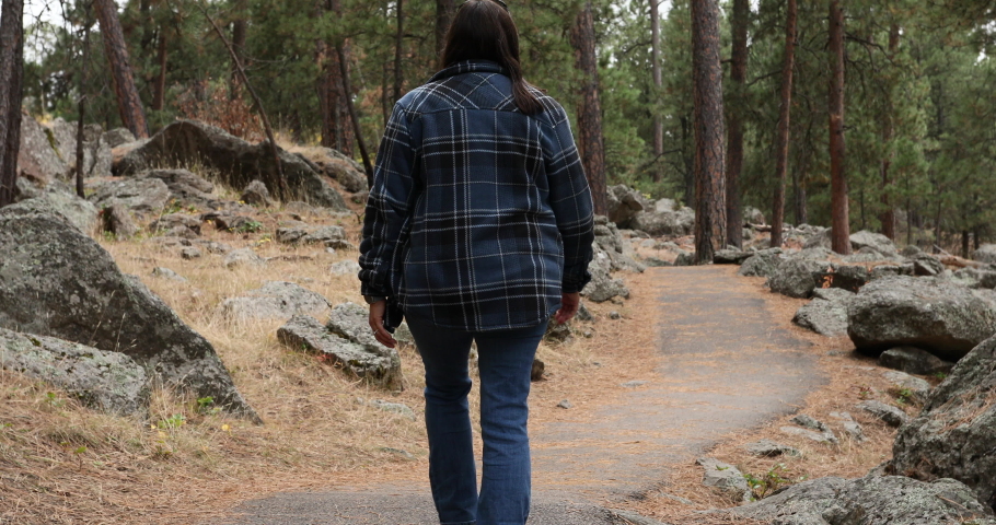 Woman hiking on trail around Devils Tower Wyoming forest 4K. 1,267 feet tall igneous rock tower in Black Hills of South Dakota and Wyoming. United States National Monument. Recreation, tourism, vacati