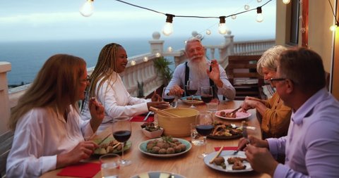 Multiracial senior friends doing dinner together at home outdoor - Slow Motion