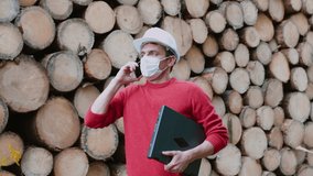 An engineer in mask is talking on phone, uses laptop. Implementation of work plan in production. There are many trees in background. COVID-19 quarantine rules at the enterprise. Telecommunication. - Powered by Shutterstock - Get 15% off with code: PIKWIZARD15