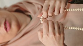 Muslim young woman praying by raising her hand and drawing a rosary. Close up rosary.
Video for the vertical story.