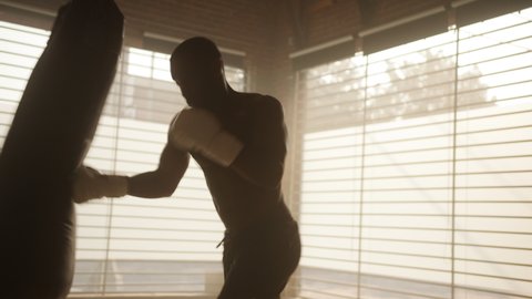Kickboxer kicking punching bag in the gym