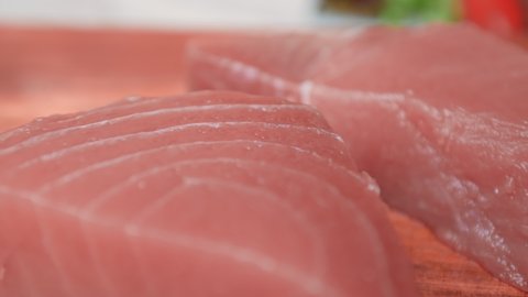 Close-up of Raw Yellowfin Tuna steaks on a wooden cutting board in 4K. Raw Tuna with cooking ingredients on a table, ready for Seared Tuna Dish.