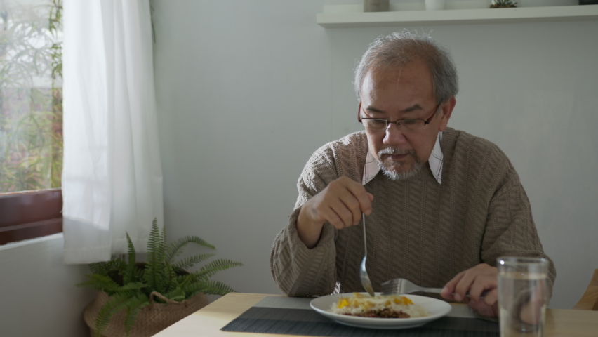 Medium shot : Sad old retired gray haired grandpa asian man sitting alone at table desk at window boring stay home self isolation quarantine feeling depress in problem mental health. Royalty-Free Stock Footage #1060787755