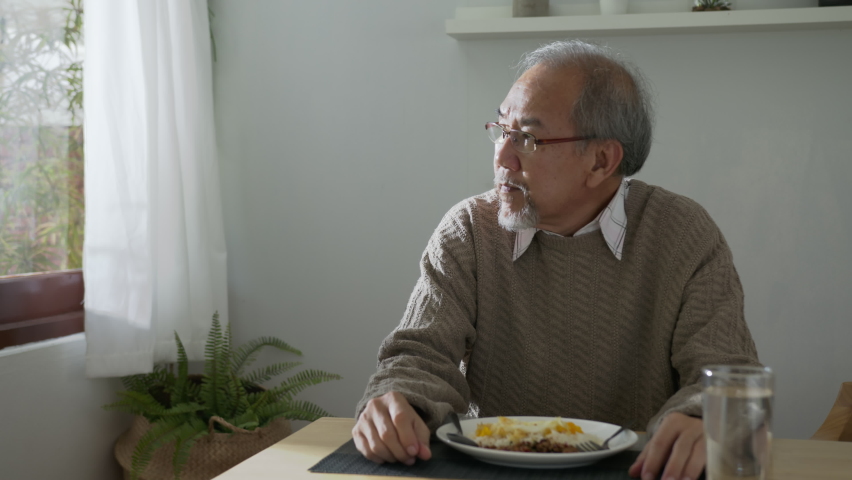 Medium shot : Sad old retired gray haired grandpa asian man sitting alone at table desk at window boring stay home self isolation quarantine feeling depress in problem mental health. Royalty-Free Stock Footage #1060787755